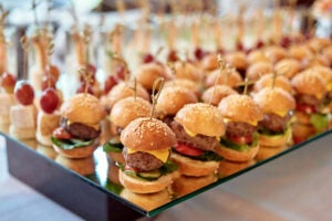 Buffet table with mini hamburgers and canape at luxury wedding reception, copy space. Serving food and appetizers at restaurant. Catering banquet table