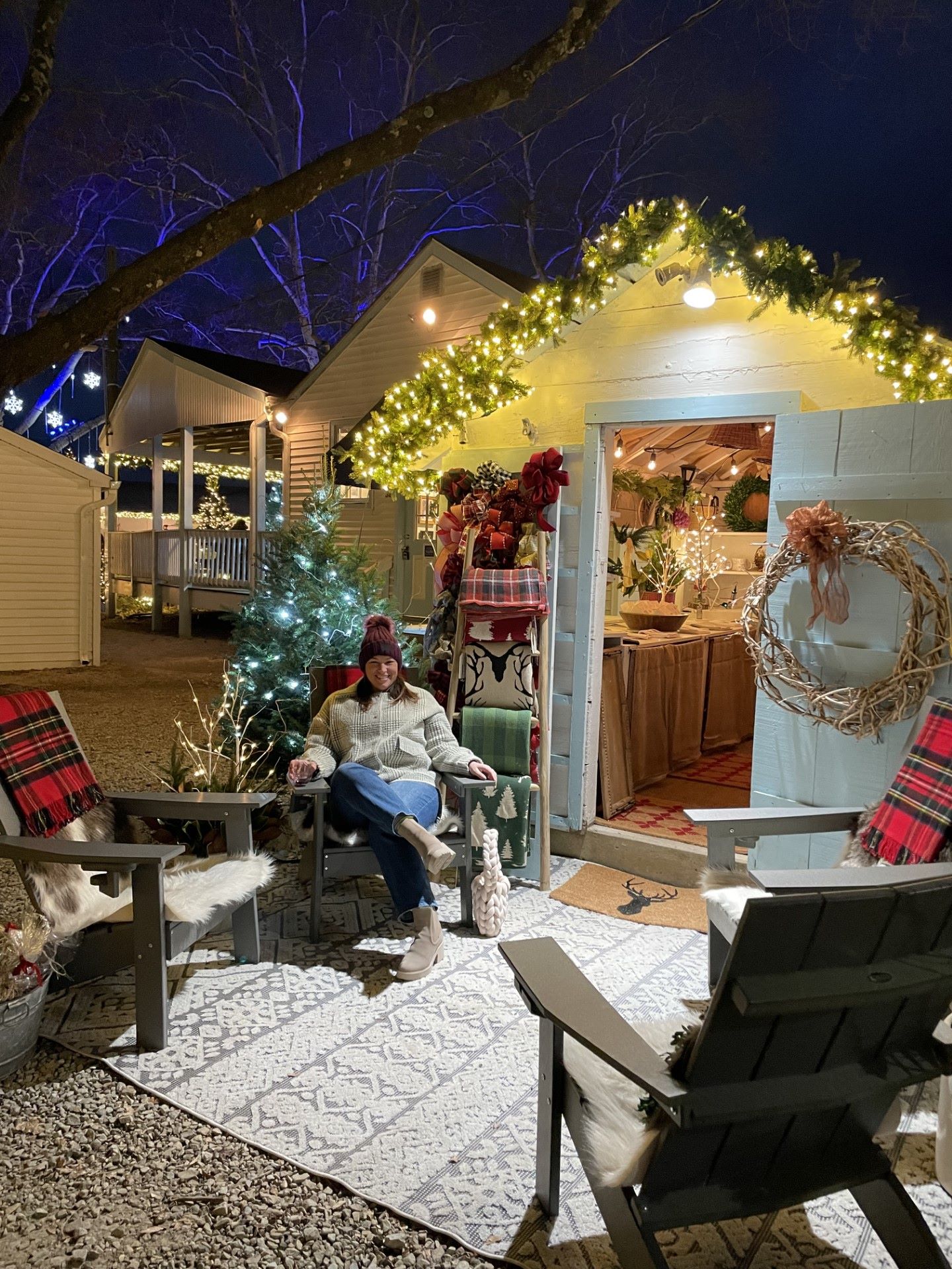 Kathy sitting outside a festively decorated cabin.