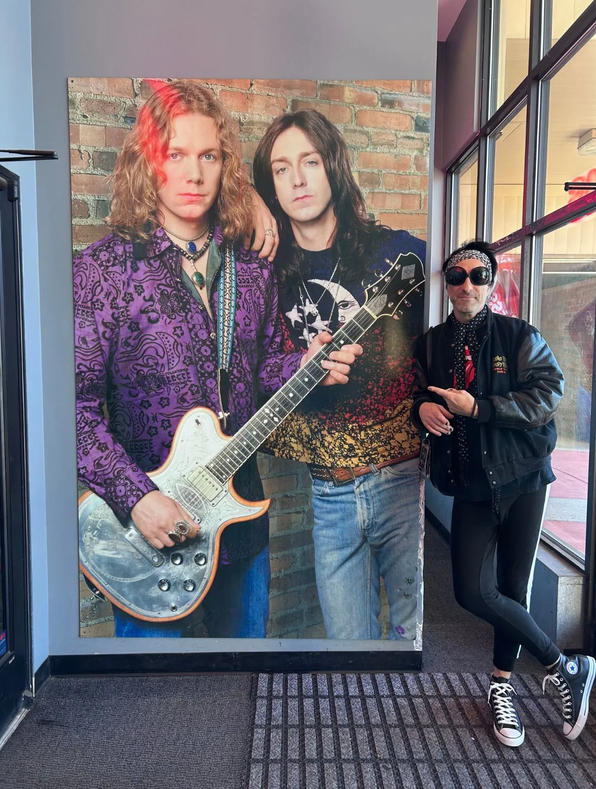 jacky standing next to a photo the black Crowes