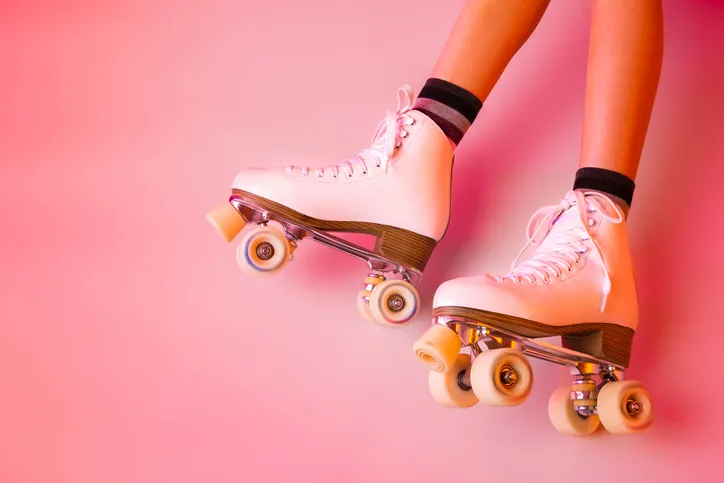 Retro classic white leather roller skates and girlâs legs - sports equipment and recreation. Pastel pink background. 