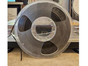 A Reel to Reel tape leaning against a record player